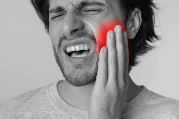 man holding his jaw in pain