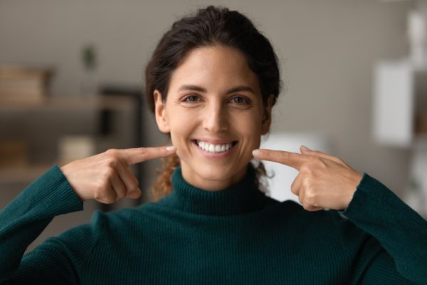 woman pointing to her smile