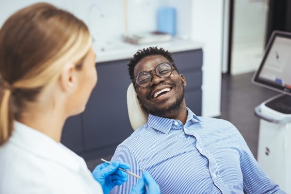 man smiling in the dental chair talking to his dentist