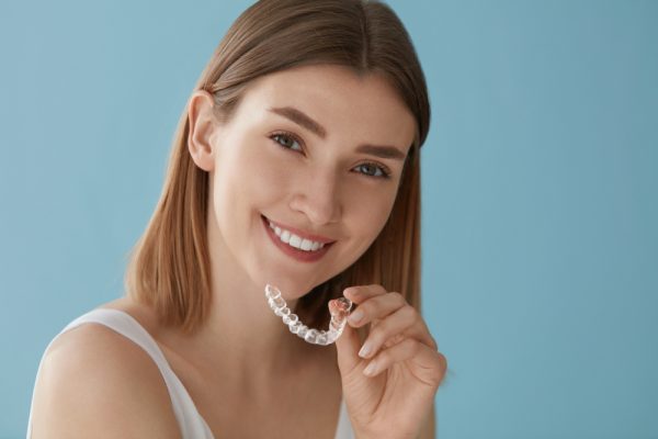 young woman holding her Invisalign aligners