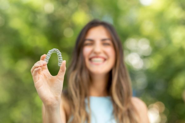 young girl holding up her Invisalign aligners.